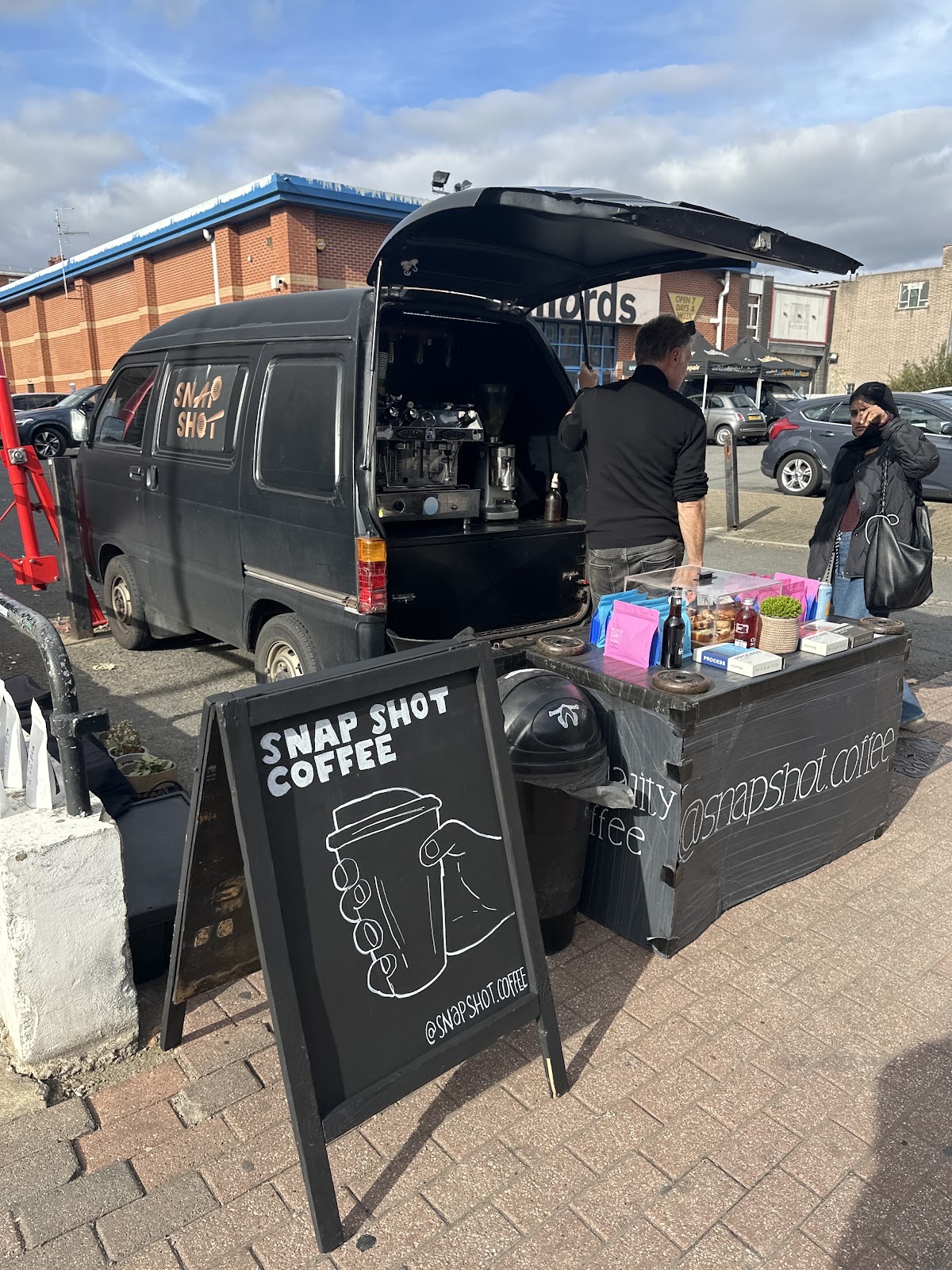 The open-back coffee van trading kerbside, a staff member working at the espresso machine