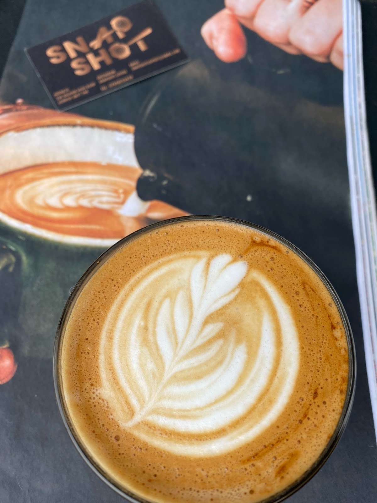 A flat white with tulip latte art in a dark cup